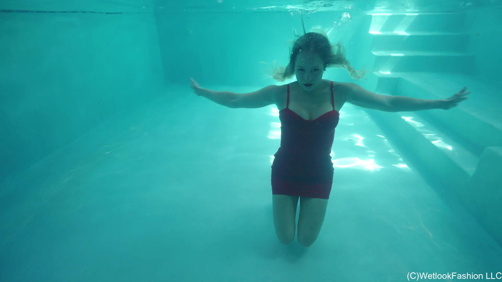 Camille trägt ein kurzes rotes Kleid im Pool