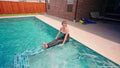 Kate taucht im Pool in einem schwarzen, glänzenden Jumpsuit