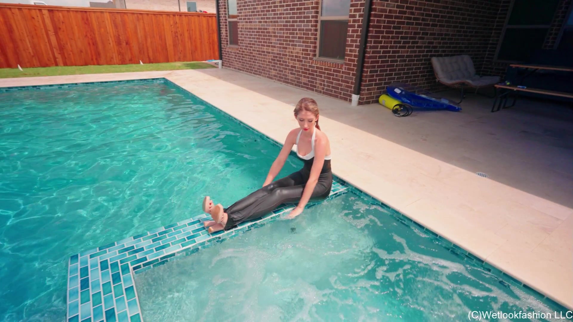 Kate taucht im Pool in einem schwarzen, glänzenden Jumpsuit