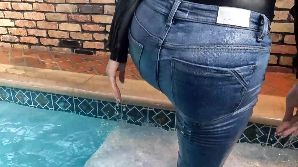 Reyna springt im Jeans und glänzenden schwarzen Oberteil in den Pool