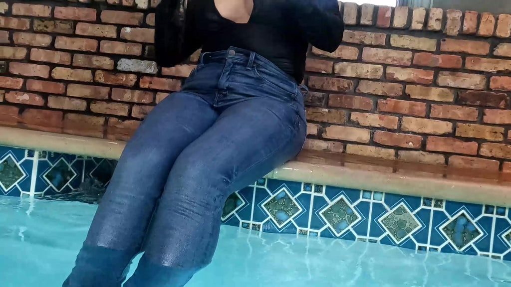Reyna springt im Jeans und glänzenden schwarzen Oberteil in den Pool