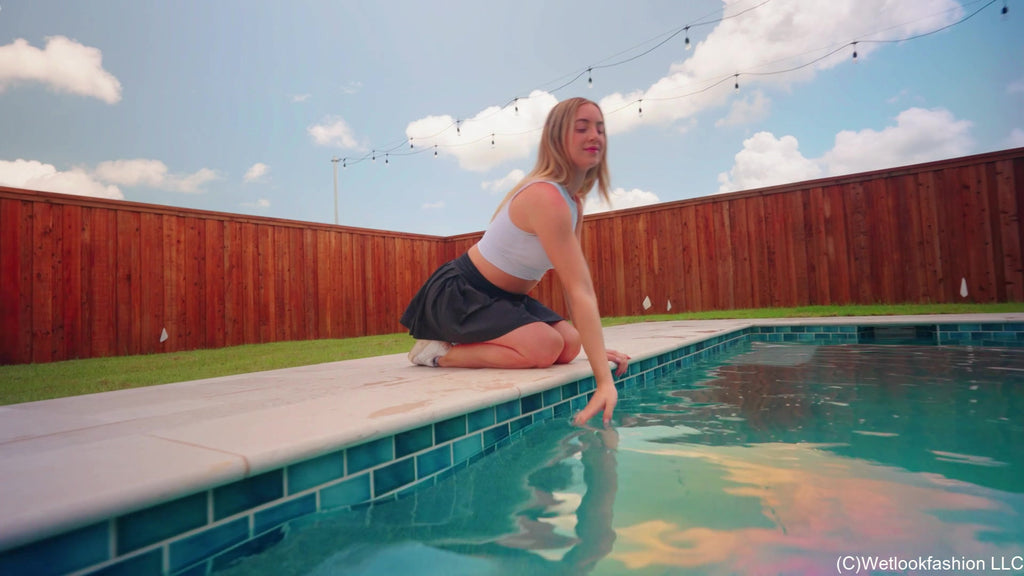 Victoria schwimmt im Pool in sportlichem Rock und Top.