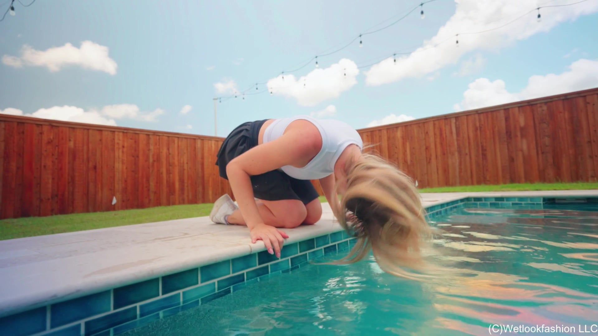 Victoria schwimmt im Pool in sportlichem Rock und Top.