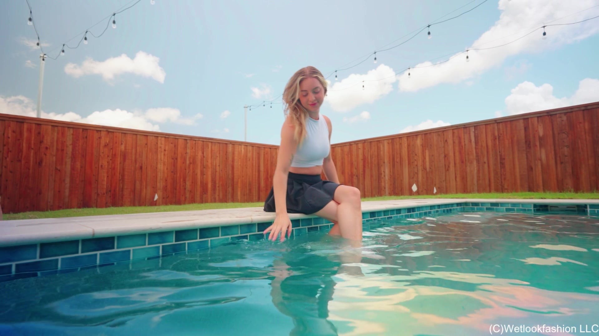 Victoria schwimmt im Pool in sportlichem Rock und Top.