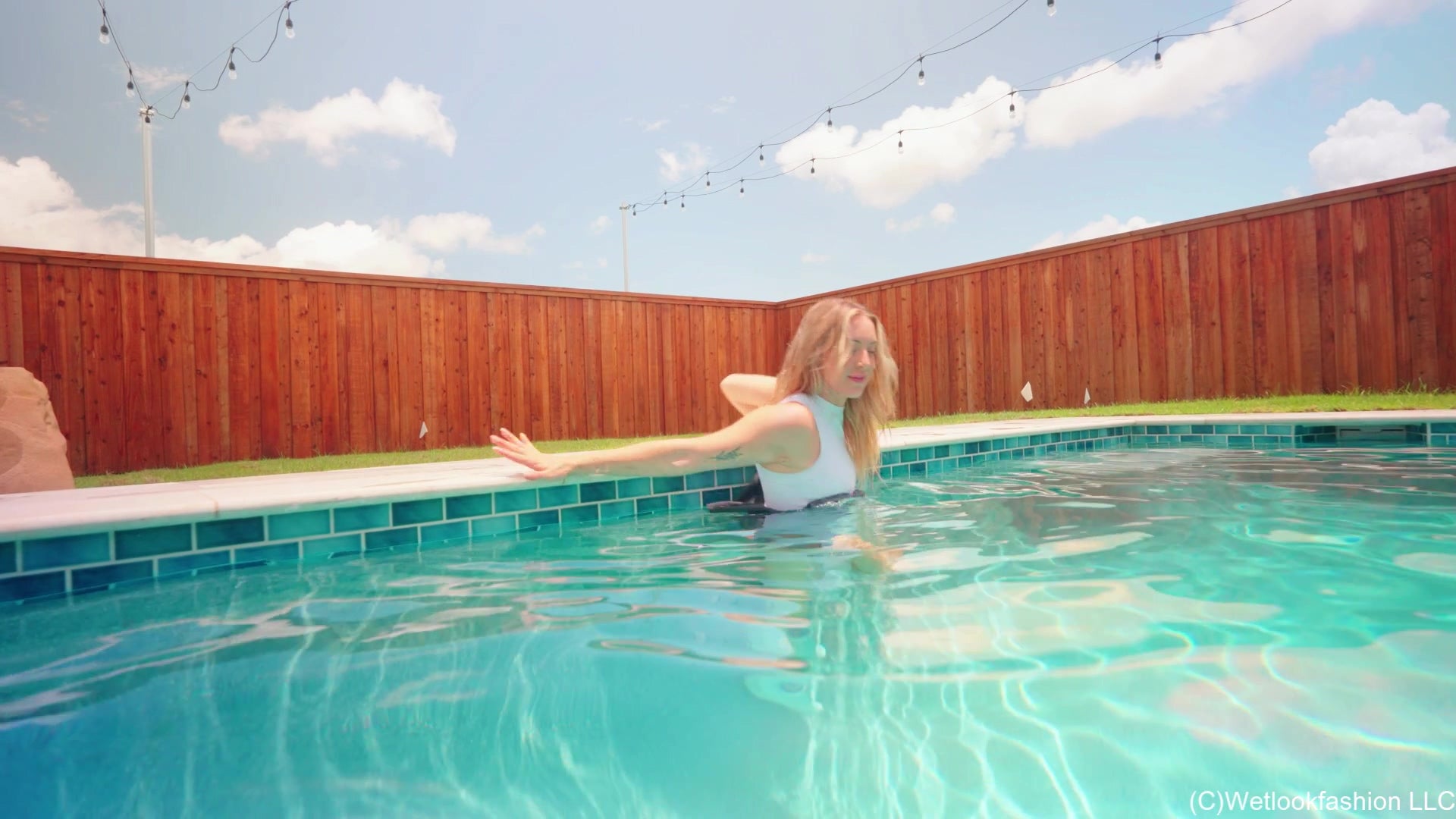 Victoria schwimmt im Pool in sportlichem Rock und Top.