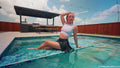 Victoria schwimmt im Pool in sportlichem Rock und Top.